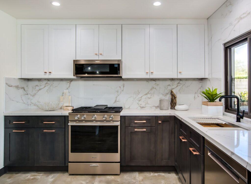A Forevermark Cabinetry kitchen with white wood cabinets and marble counter tops.