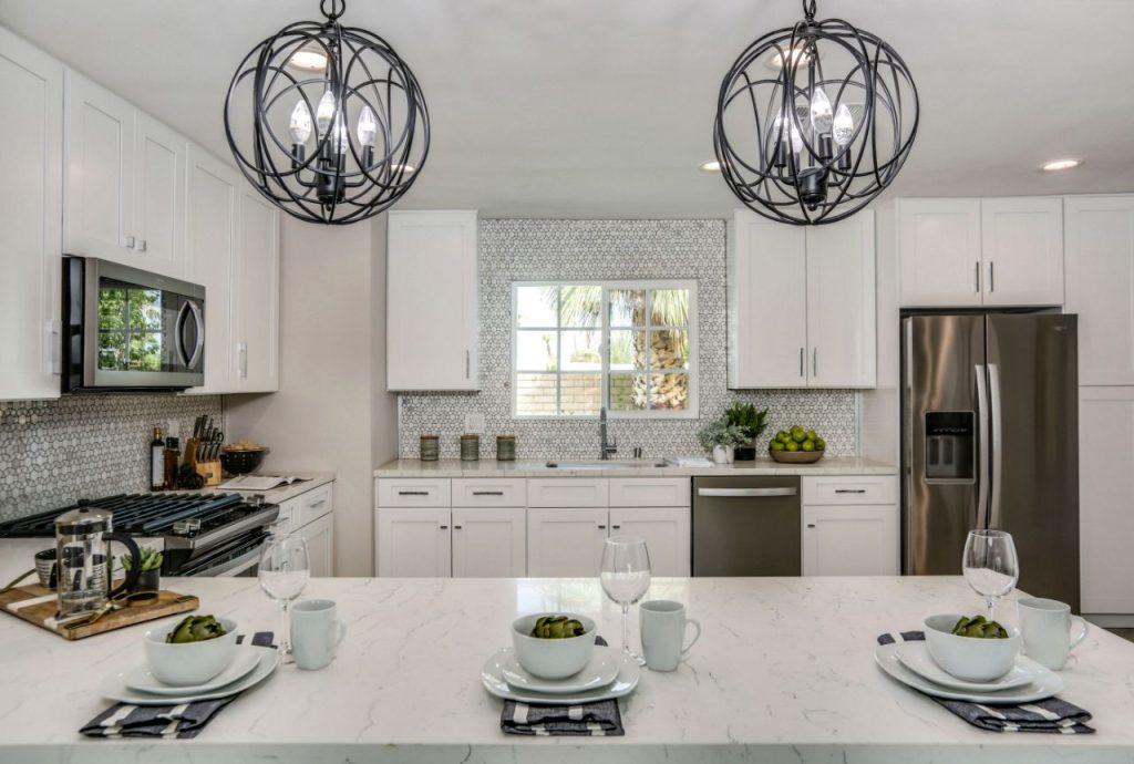 a kitchen with white cabinets and a chandelier built by forevermark cabinetry
