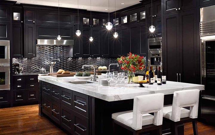 A kitchen with Forevermark Cabinetry black kitchen cabinets and marble counter tops.