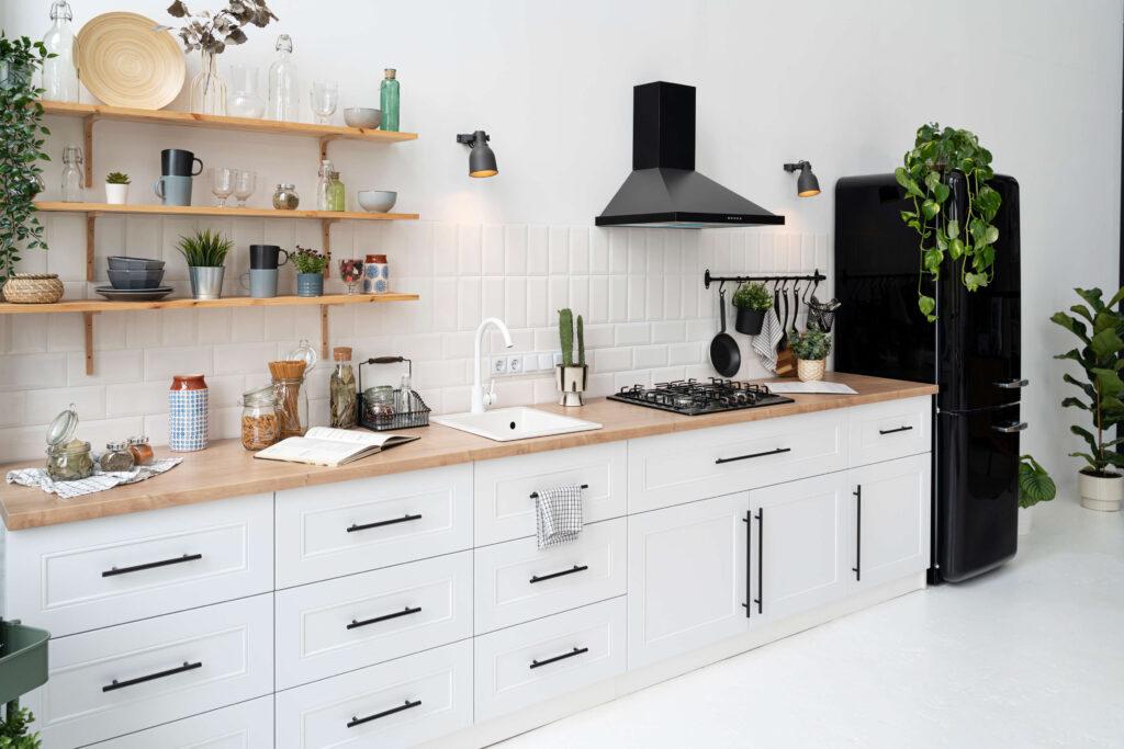 A white kitchen with black appliances, plants, and Forevermark Cabinetry.