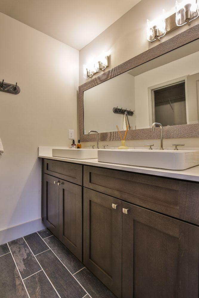 a bathroom with two Forevermark Cabinetry wood cabinetry sinks and a mirror.