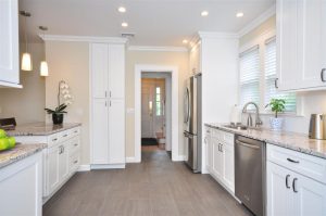 A kitchen with white Forevermark Cabinetry cabinets and granite counter tops.