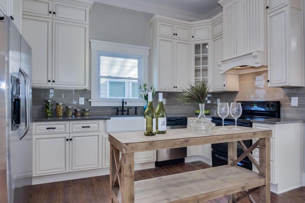 a kitchen with white interior, wooden table and white cabinets made by forevermark cabinetry