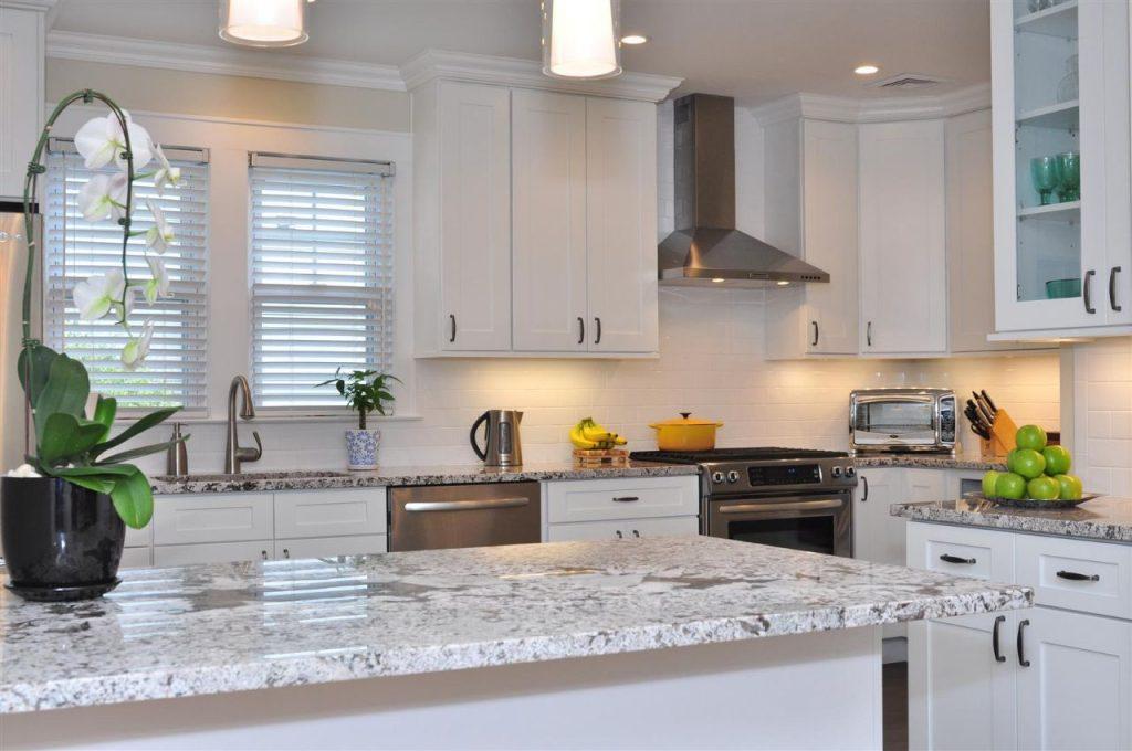 a kitchen with marble island and a beautiful white wooden cabinets of forevermark cabinetry