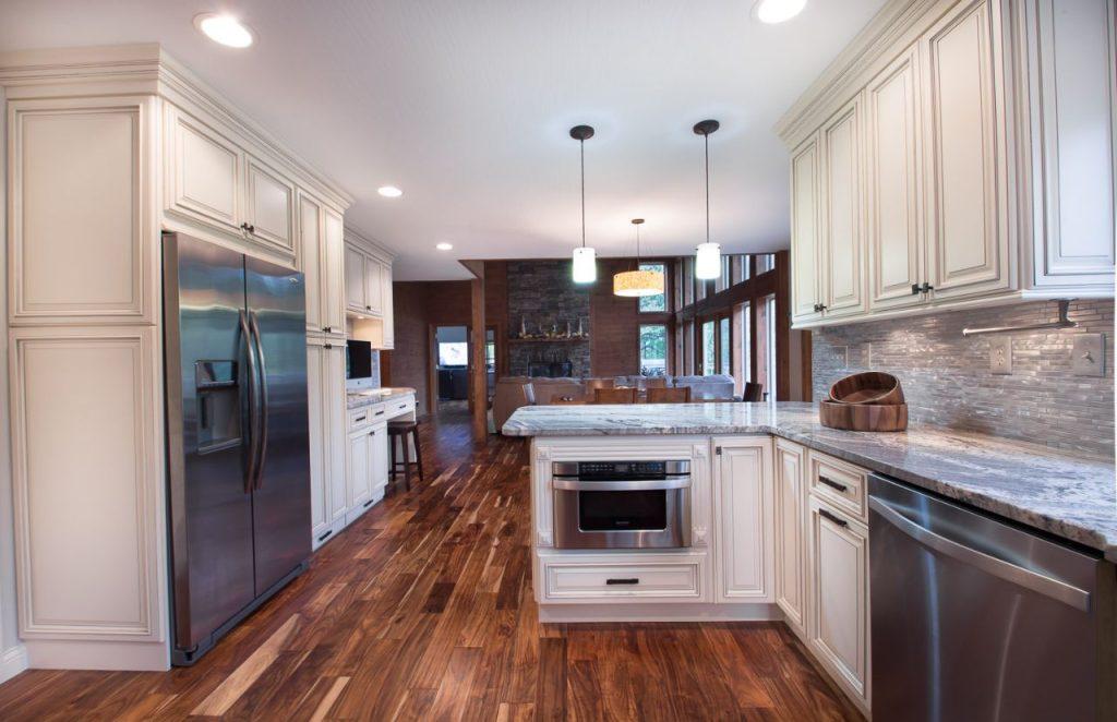 a wooden kitchen flooring with marble island and wooden cabinets by mykitchencabinets