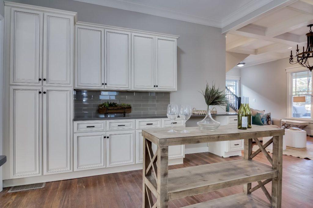 a kitchen with small wooden island and white wooden cabinets by mykitchencabinets