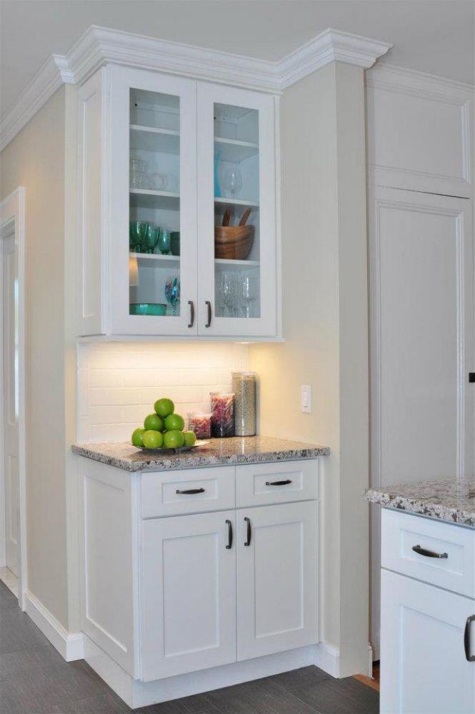 corner of a white kitchen interior with marble islands and white wooden cabinets by mykitchencabinets