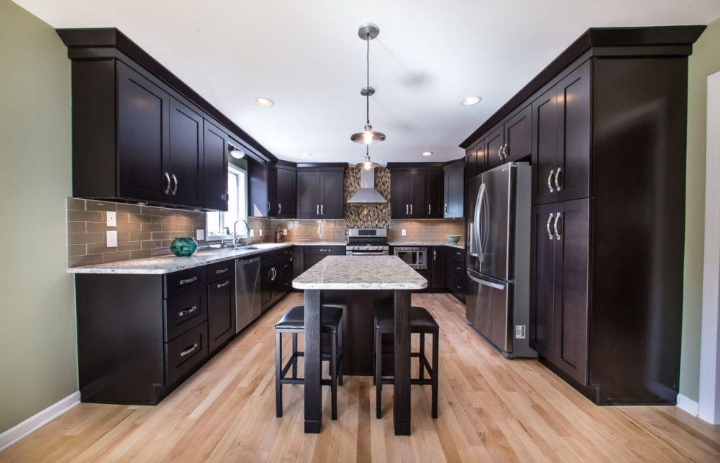 a kitchen with marble dining table and black wooden cabinets by mykitchencabinets