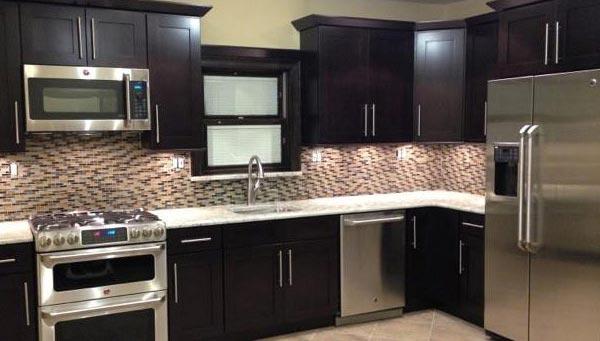 a kitchen with marble sink and black wooden cabinets installed by mykitchencabinets