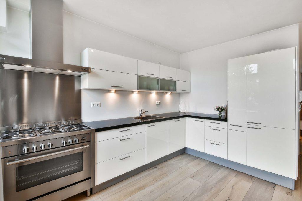 a white kitchen interior design with dark marble sink and white wooden kitchen cabinets