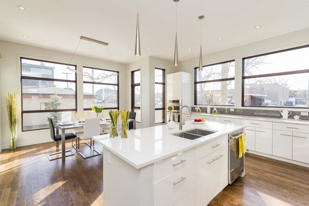a kitchen with glass windows, white marble island and white wooden kitchen cabinets intalled by mykitchencabinets