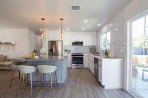 a white kitchen interior with small marble island and white wooden cabinets by mykitchencabinets